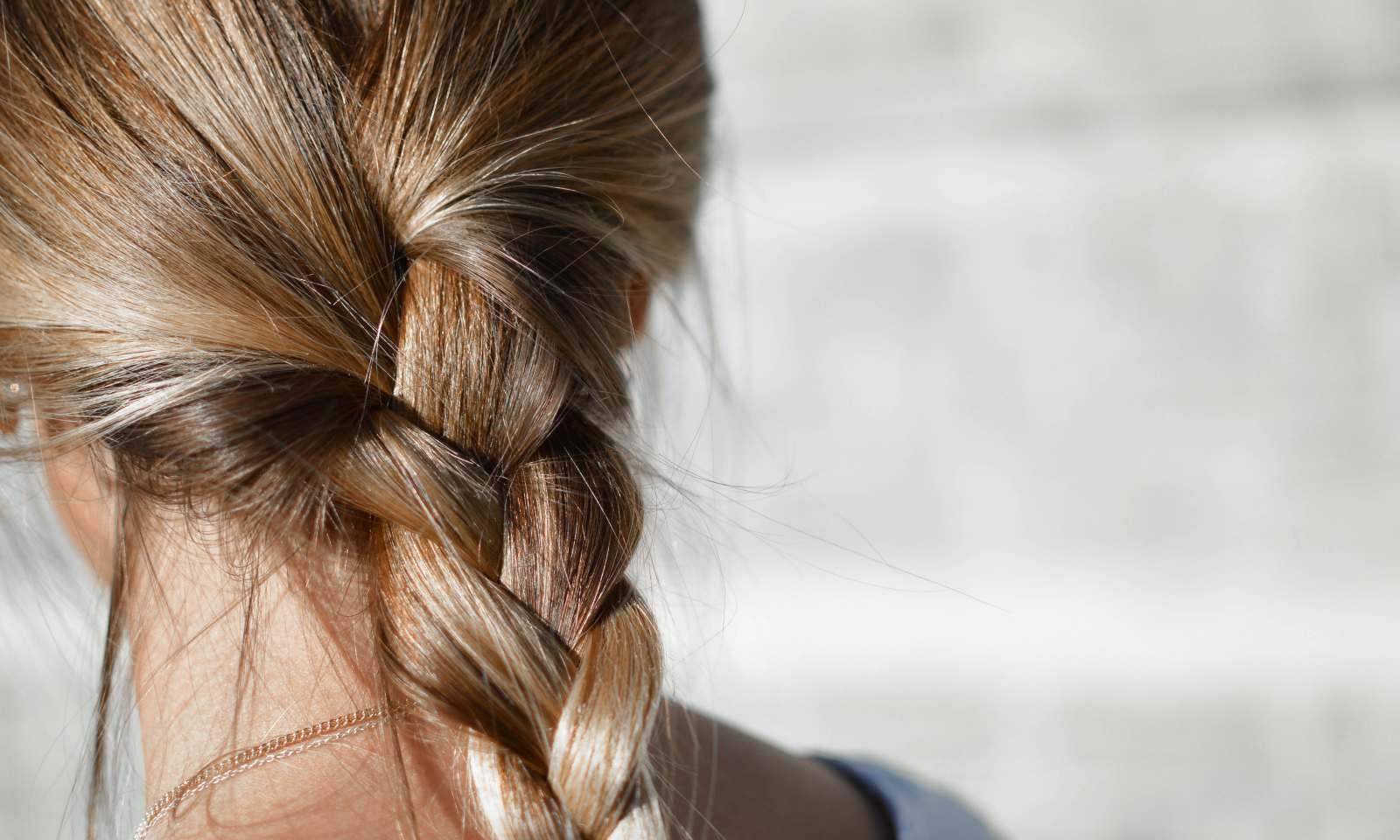 ragazza con capelli fini biondi legati in una treccia