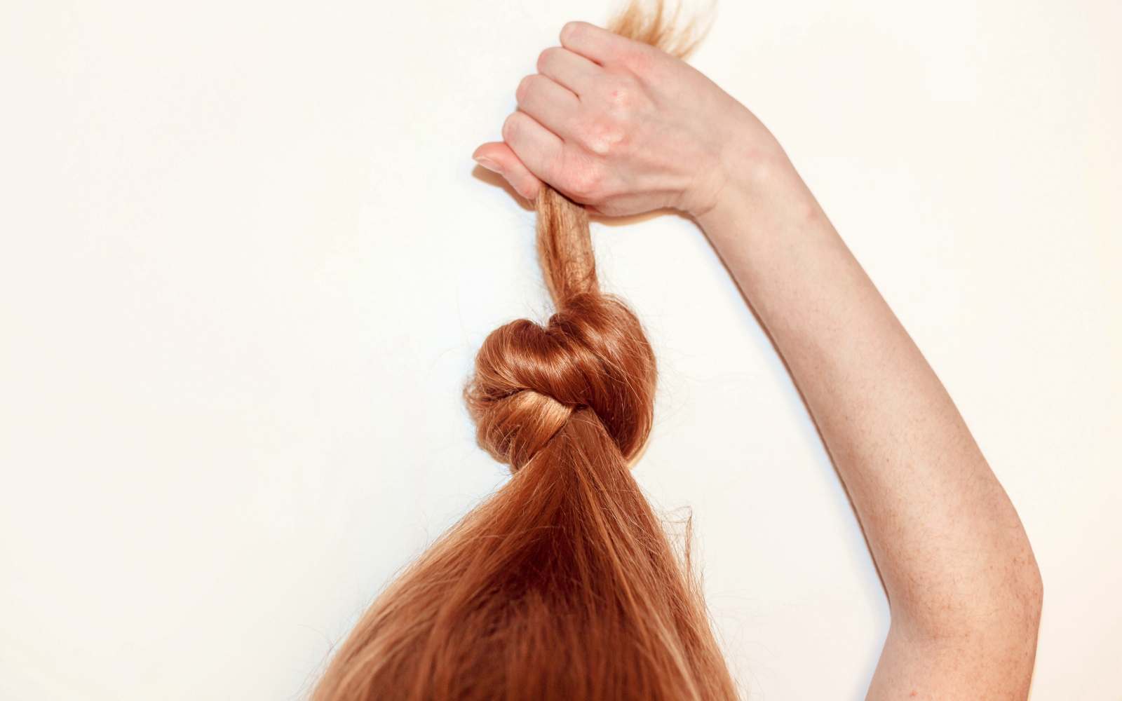 nodo di capelli rossi forti tirato dalla mano di una ragazza