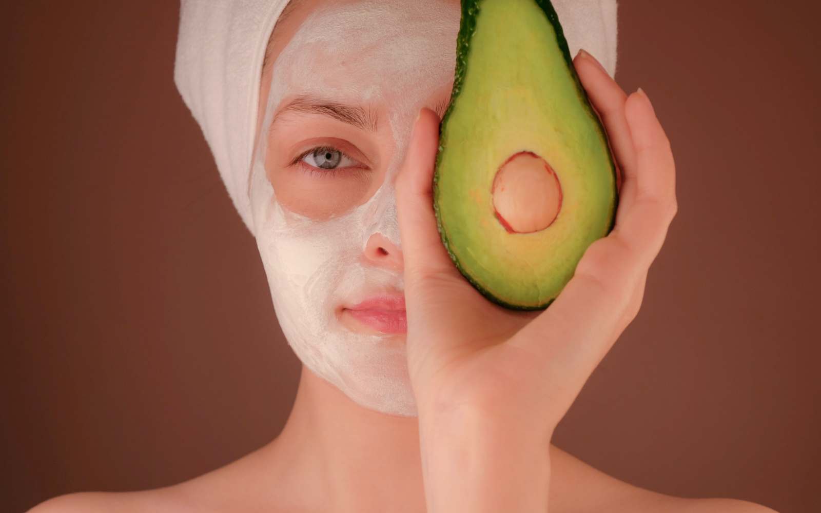 ragazza con avocado, maschera per viso bianca e turbante bianco con maschera per capelli all'avocado
