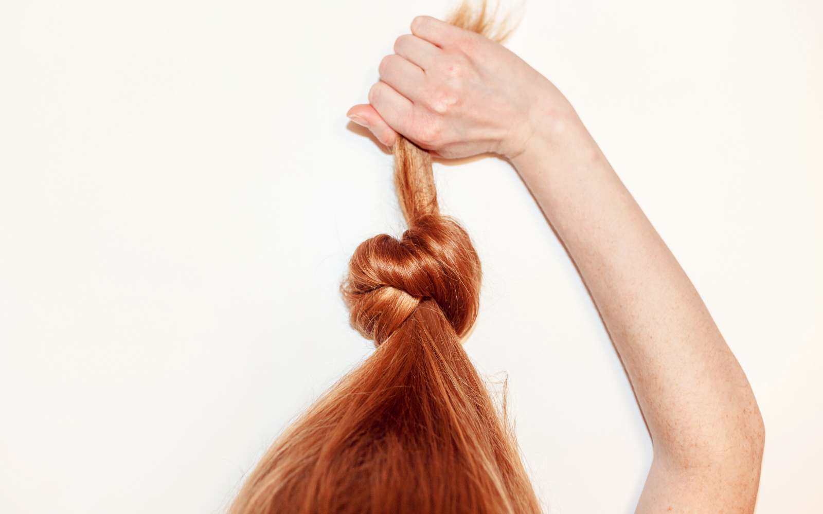 capelli rossi legati tirati verso l'alto dalla mano della ragazza