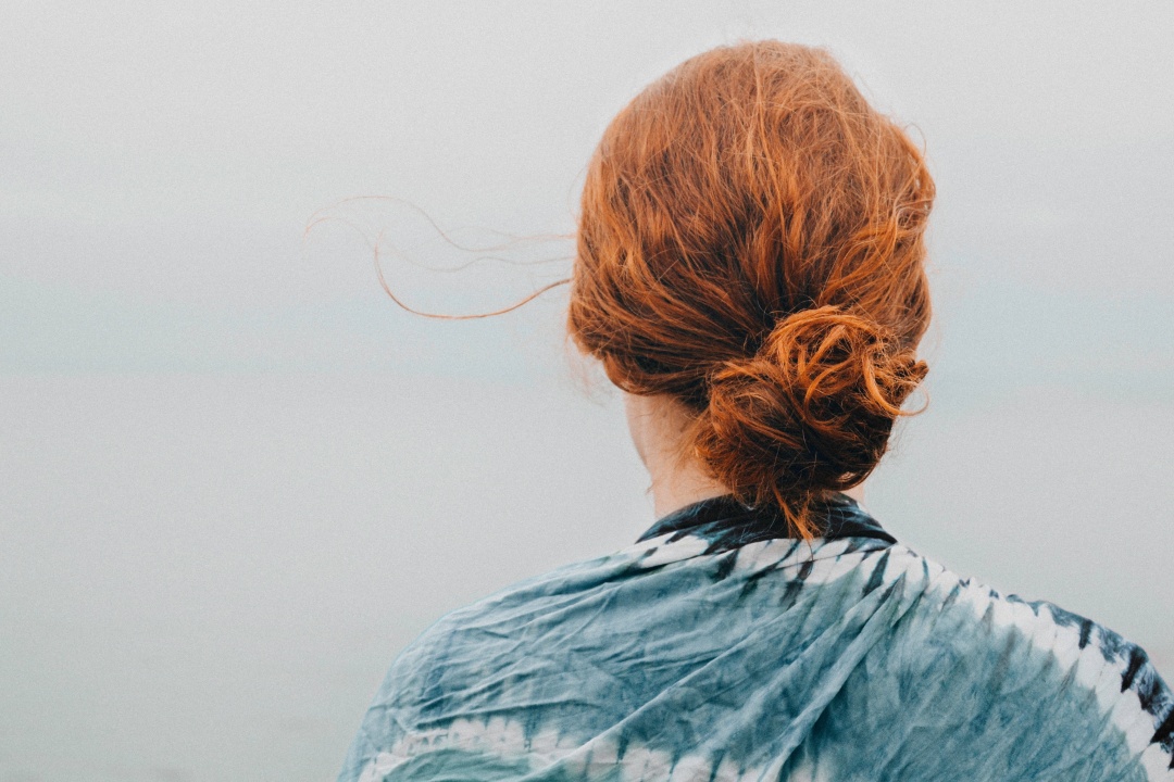 ragazza di spalle con capelli rossi legati crespi