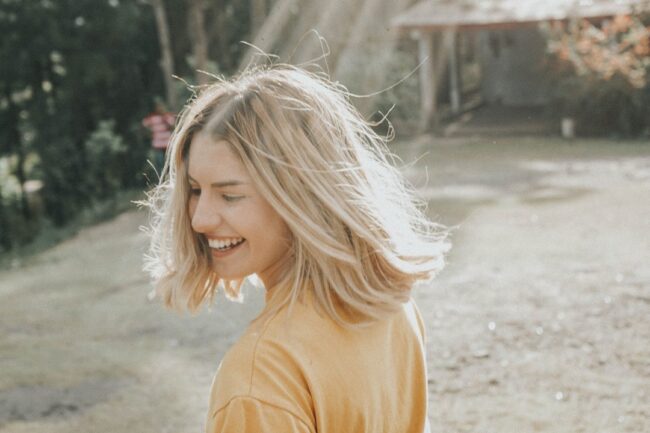 ragazza con capelli biondo tinti su base castana ride