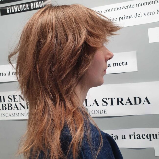 ragazza di profilo con capelli castani e taglio wolf cut