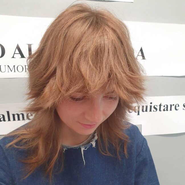 ragazza di profilo con capelli castani e taglio wolf cut