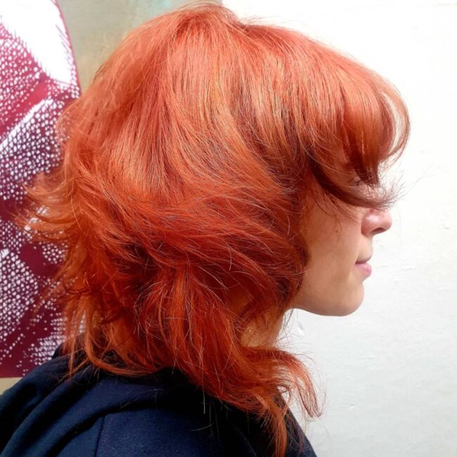 ragazza di profilo con capelli rossi e taglio wolf cut