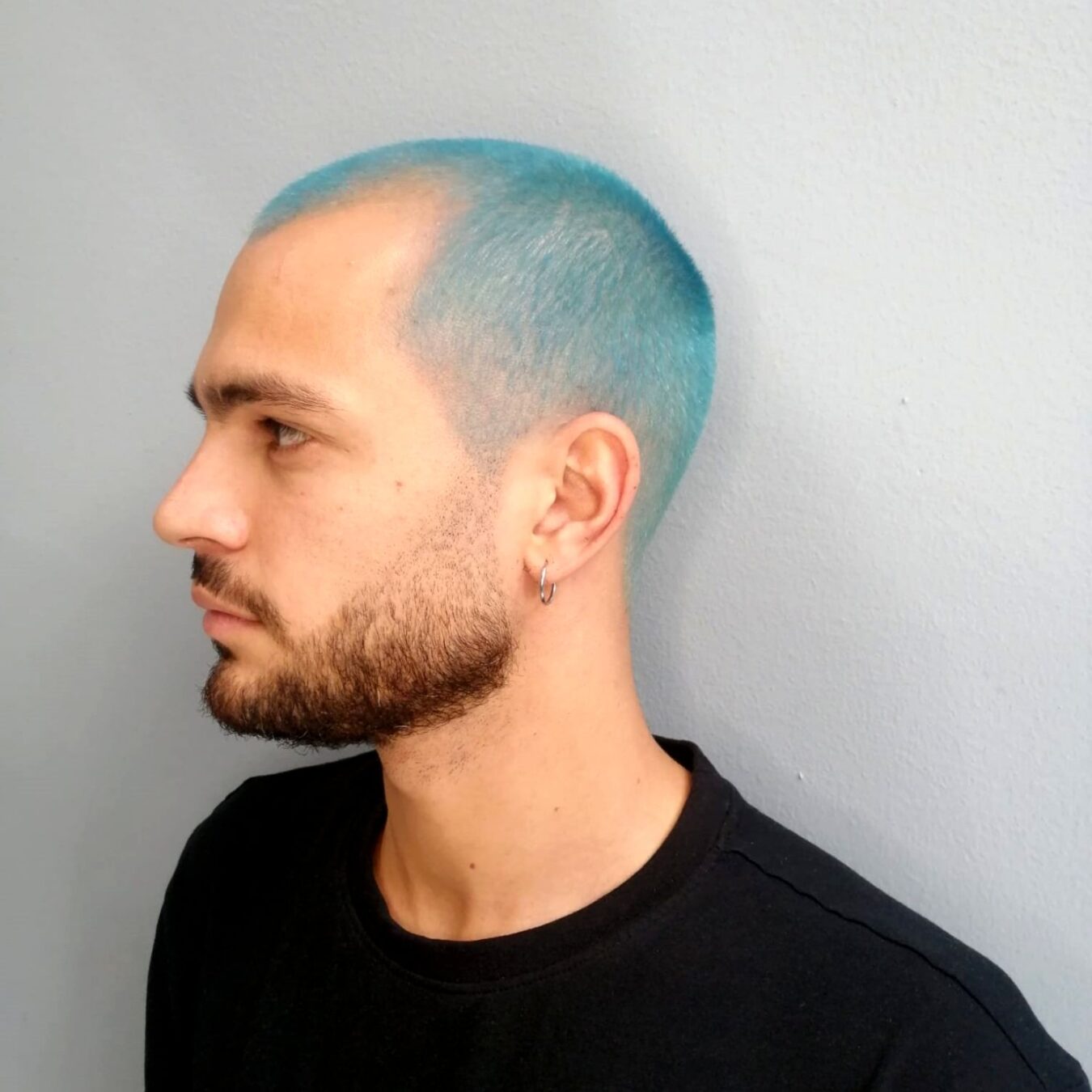 ragazzo di profilo con taglio buzz cut corto azzurro