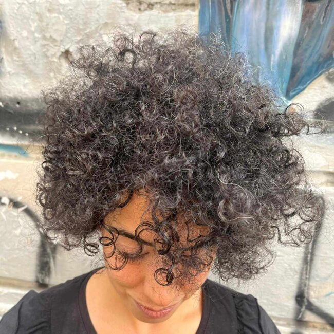 ragazza con capelli ricci neri e maglia nera