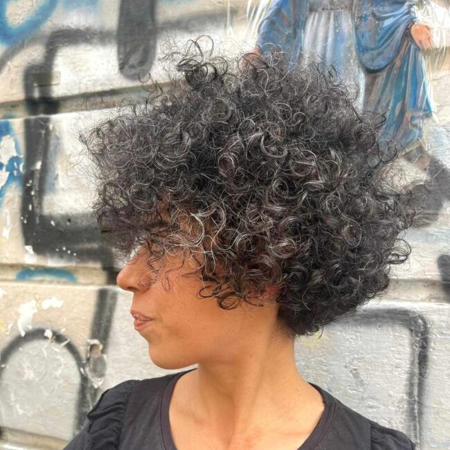 ragazza di profilo con capelli ricci neri e maglia nera